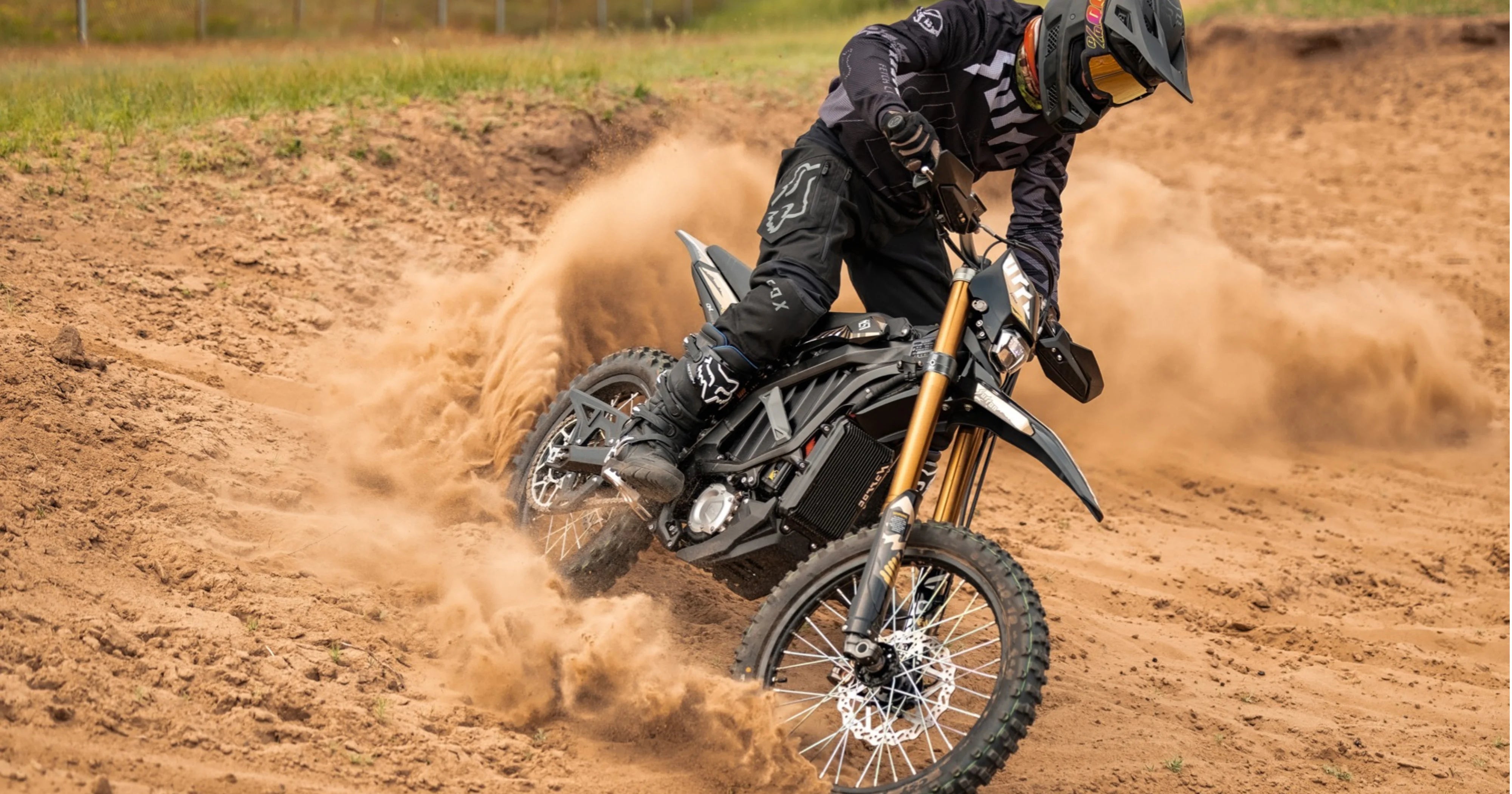 Person riding a surron ultrabee dirt bike on a dirt track with dust in the air