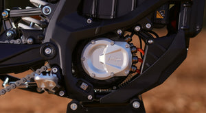 Close-up of a surron ultrabee motorcycle engine and chain on a blurred background