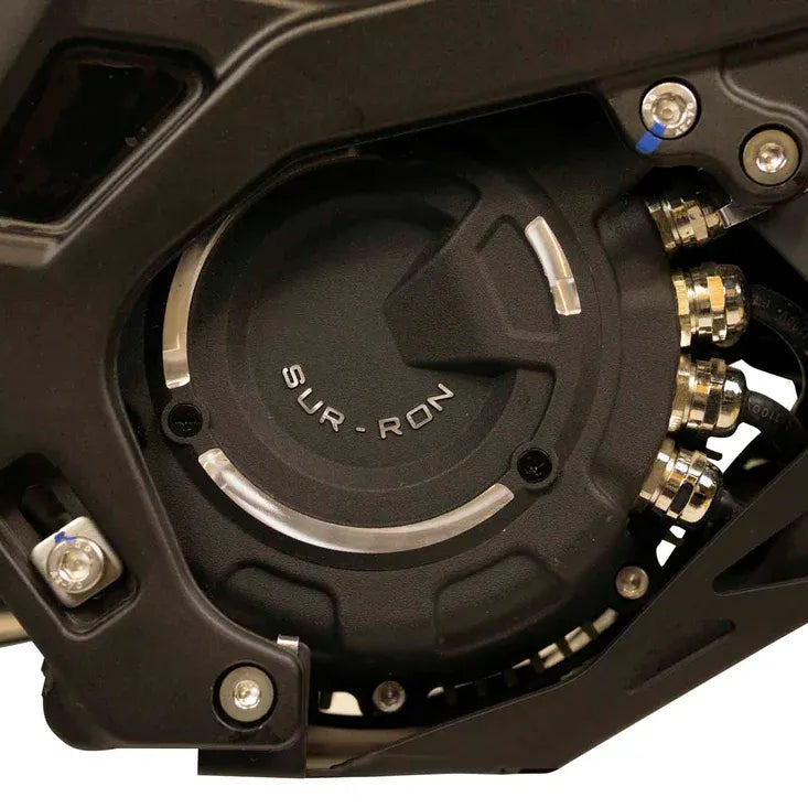 Close-up of a motorcycle engine with 'Sur Ron' branding on a white background