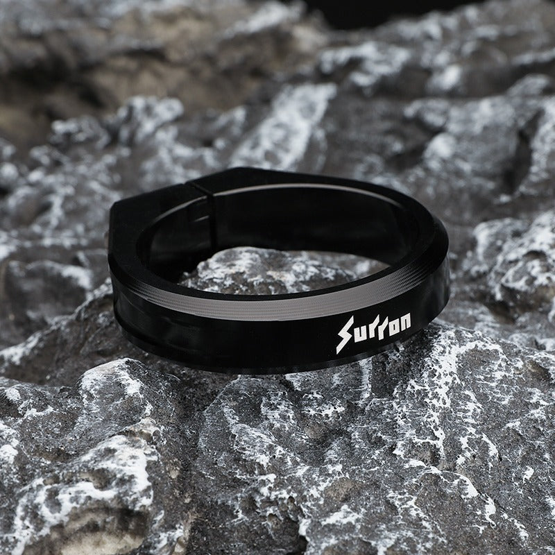 Black ring with 'Sutton' branding on a rocky surface