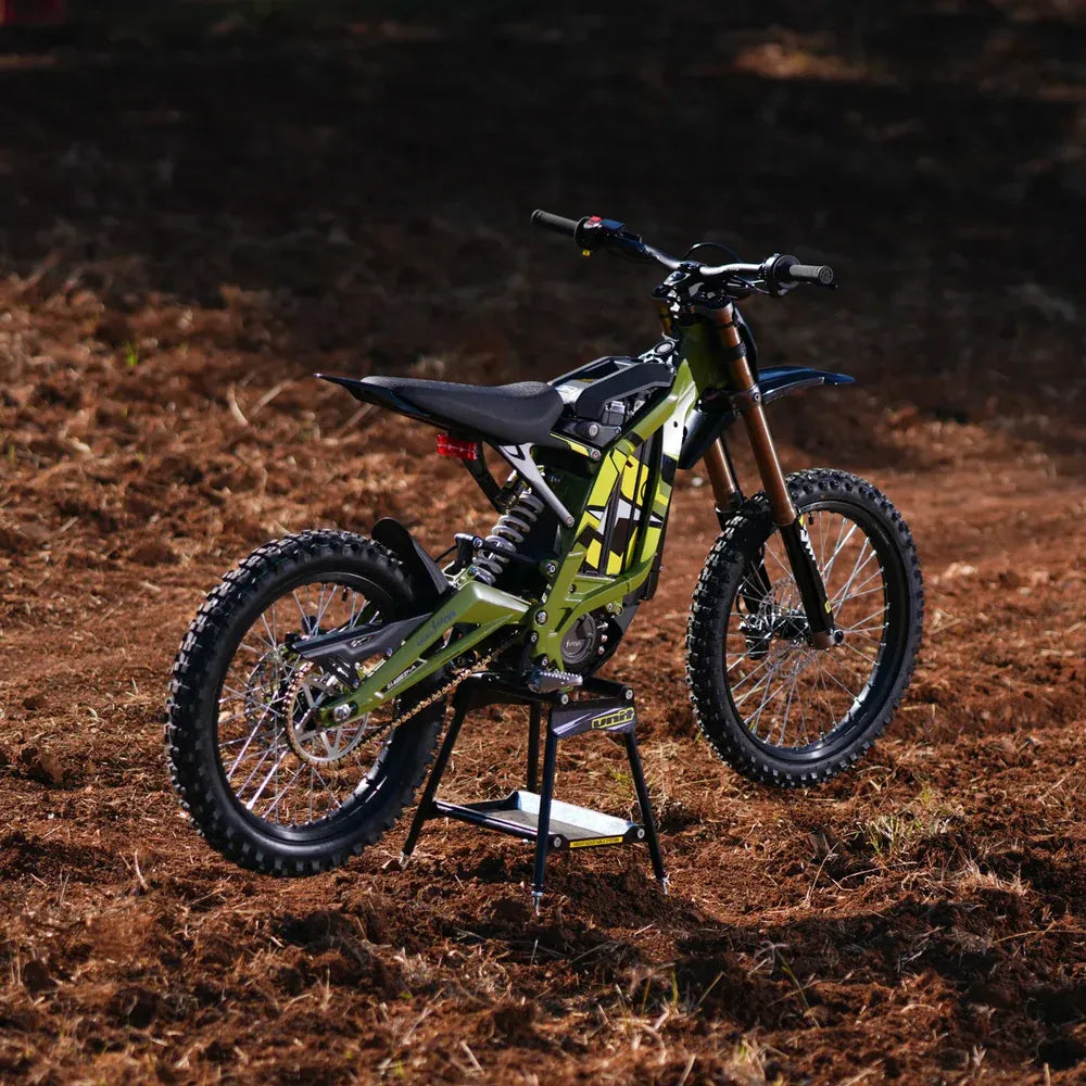 surron 2025 lightbee x  Green dirt bike on a stand in a muddy outdoor setting
