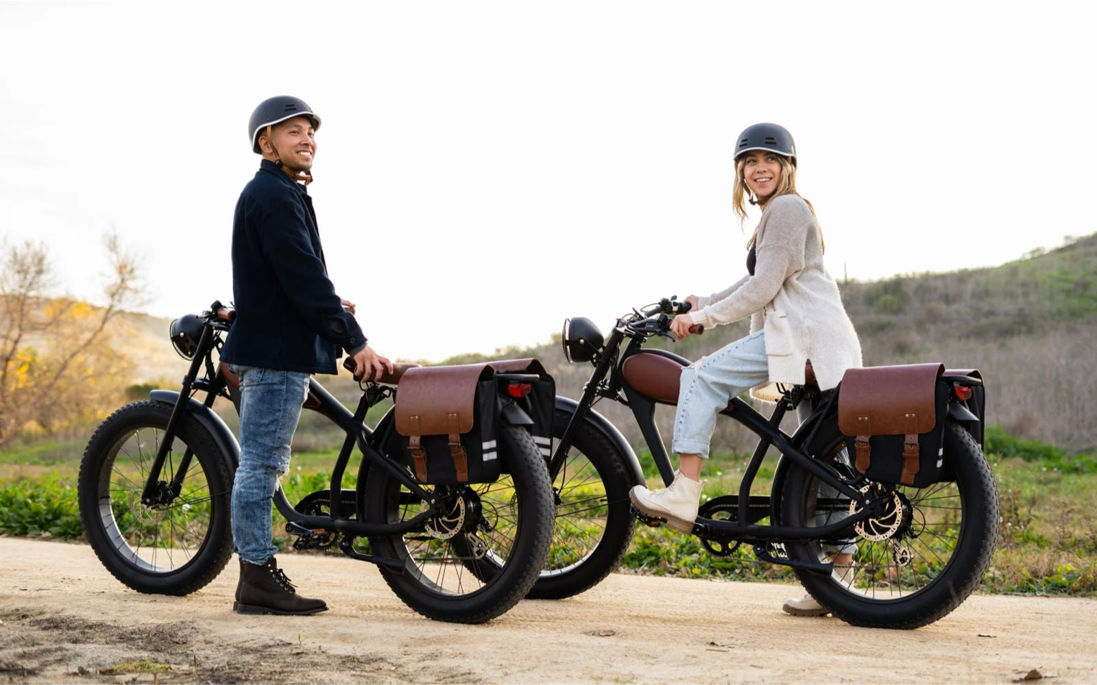 Two people standing next to revi vintage electric bikes on a wooden platform with a natural landscape in the background.