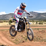 Motorcycle rider in action on a dirt track with mountains in the background