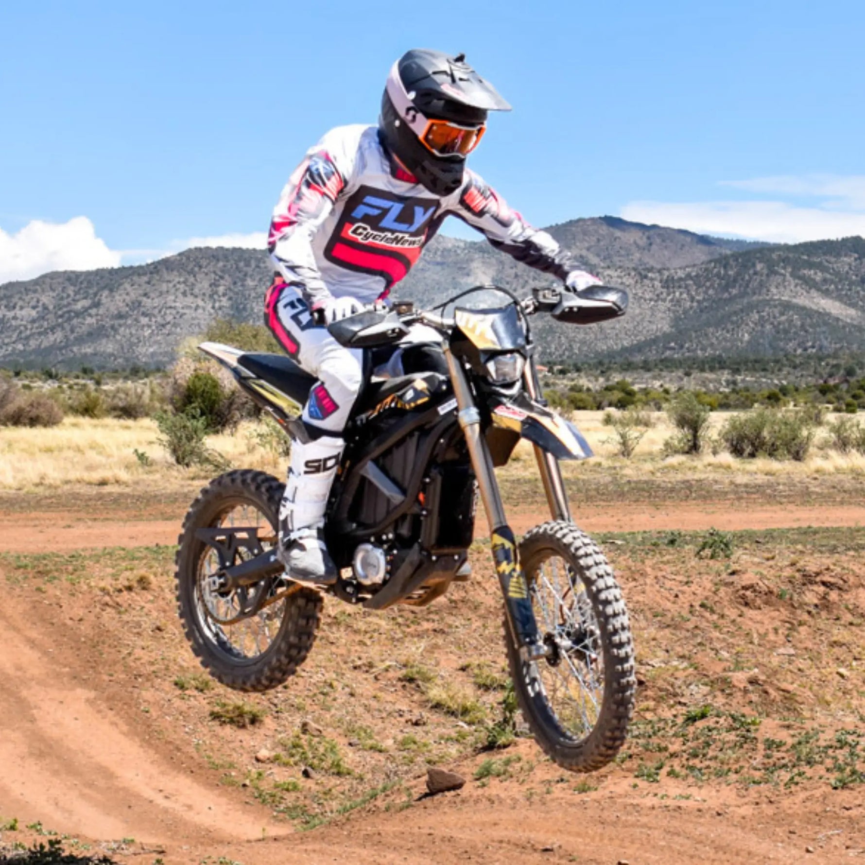 Motorcycle rider in action on a dirt track with mountains in the background